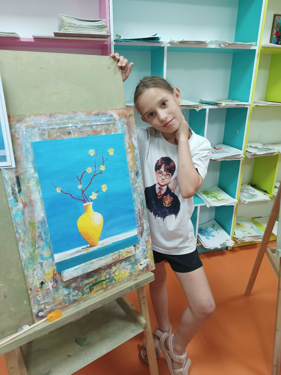 Elizaveta Krutchenko holding one of her paintings in the studio
